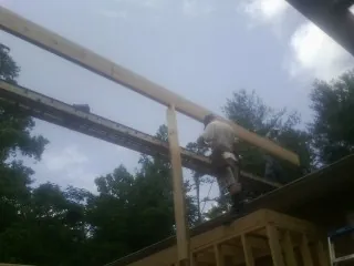 Carpenter setting a ridge beam over a new addition frame — Ice Dam Removal by Roofing Brothers in Fennville