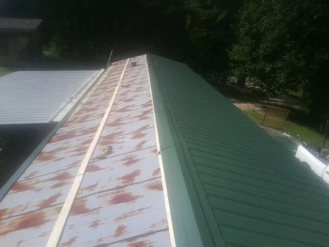 Old rusted panels beside newly installed green metal roofing — Wind Damage Roof Repair by Roofing Brothers in Fennville