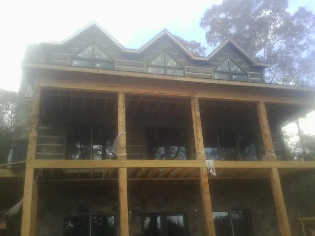 Dormers and porch framing on a large log home under construction — Roof Coating work by our crew in Fennville