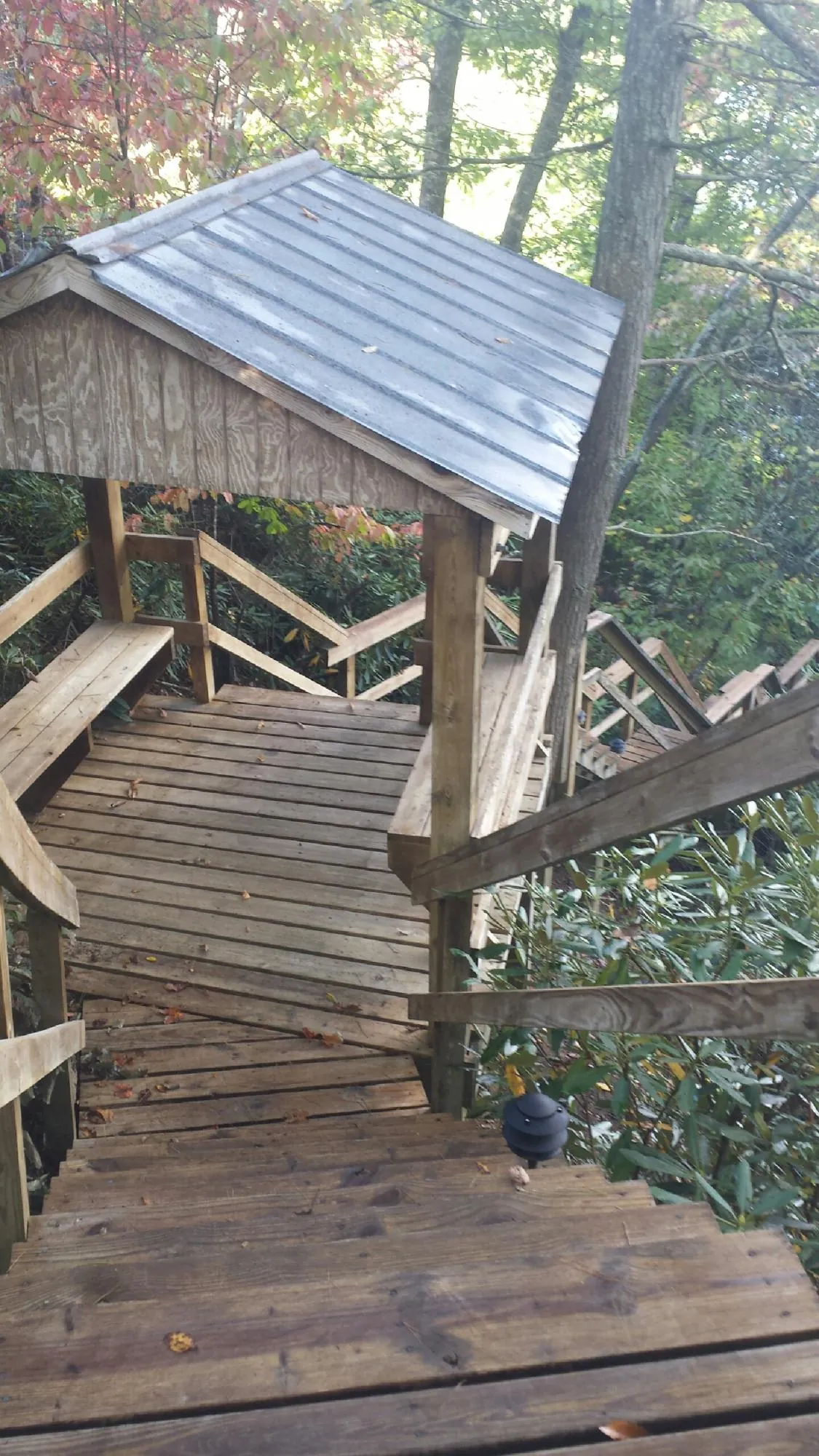 Metal roofed shelter over wooden steps on a wooded walkway — Skylight Repair & Installation work by our crew in Fennville