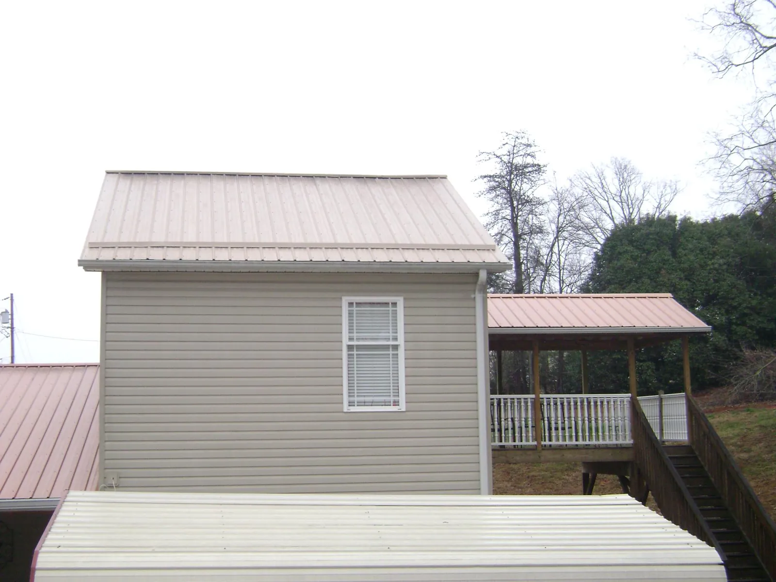 Tan metal roofs on a two story addition and attached porch, from a Roof Replacement job in Fennville