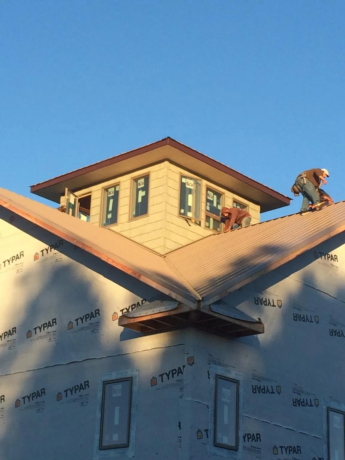 Roofers working around a rooftop cupola on a new metal roof at sunset — Roof Waterproofing in Fennville by Roofing Brothers
